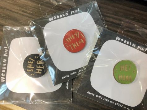 Pins depicting different pronouns that people can use to normalize asking and telling pronouns. 