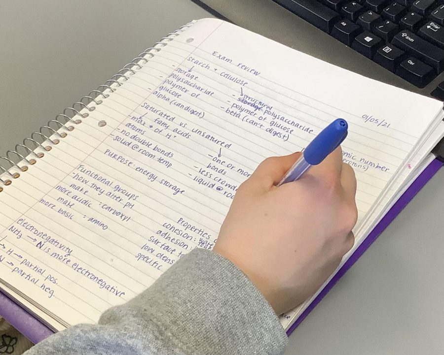 A student takes notes to prepare for a final exam in the winter of 2022.