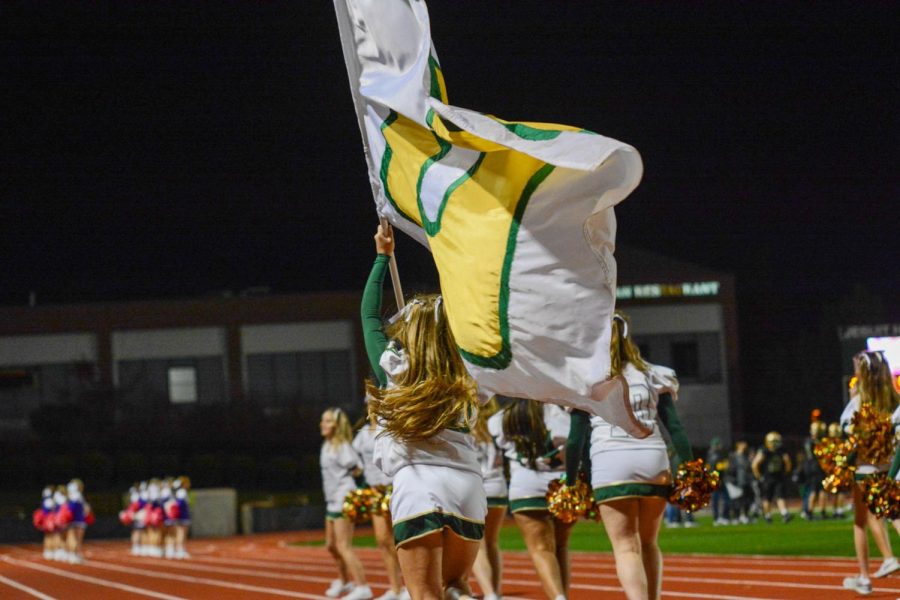 Varsity+cheerleader+Courtney+Jones+carries+the+Jesuit+flag+at+the+2021+homecoming+football+game.