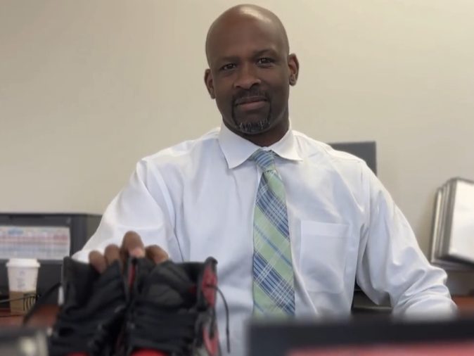 Principal Maxie poses in his office with his signature Air Jordan shoes.