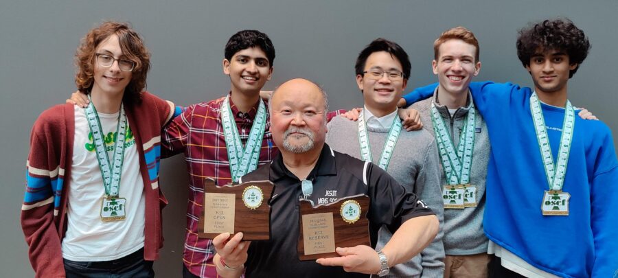 The varsity chess team (Will Nobles 26, Roshen Nair 24, Harry Zhou 23, Conner Jensen 24, and Rohan Sastry 24) holding their championship trophies with Coach Al Kato.