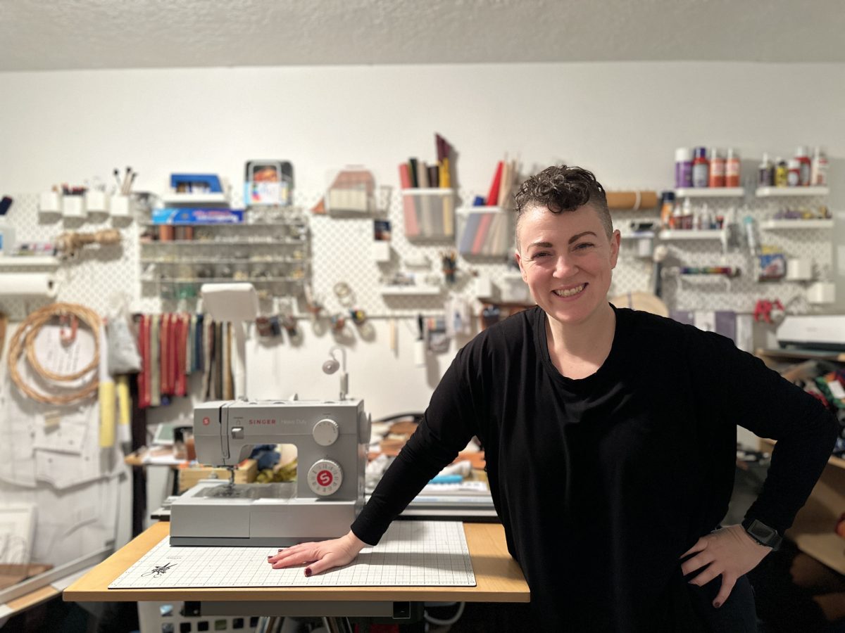 Ms.+Schick+stands+in+front+of+her+home+studio%2C+surrounded+by+craft+supplies%2C+tools%2C+and+machines.